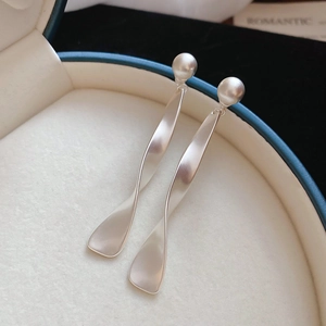 Vue macro de boucles d'oreilles ruban en argent mat avec perles rondes élégantes