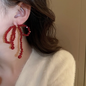 Vue détaillée d'une femme portant des boucles d'oreilles nœuds en perles rouges