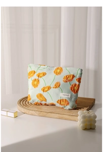 Close-up of floral canvas makeup bag with orange poppy print on a wavy wooden tray
