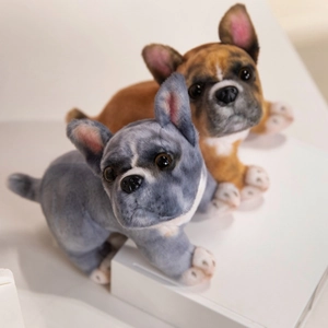 Realistic French Bulldog plush toy pair in grey and tan spots on a white pedestal