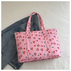 Detail of pink tote bag with red cherry print on casual denim jacket background