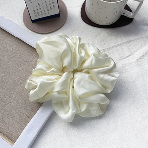 Oversized cream white satin scrunchie shown in a minimalist lifestyle setting with soft fabric