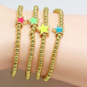 Set of four gold beaded bracelets with colorful enamel star charms on a female wrist