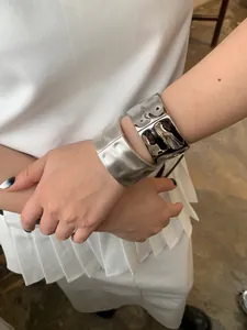 Detail of wide silver alloy bangles featuring mirror polished and brushed matte textures