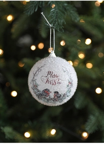 Close-up of a white textured Christmas ball with bird illustration on a pine tree branch