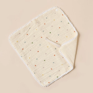 Detail of cotton baby bib with colorful polka dots, pom pom trim and handy neck strap