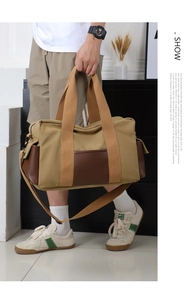 Detail of khaki canvas and brown leather travel bag held by a model for size