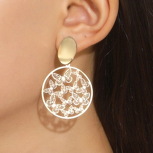 Detail of elegant gold hollow butterfly hoop earrings worn on a female model