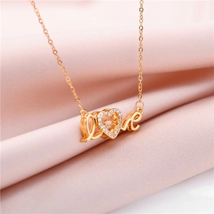 Macro shot of gold LOVE pendant with sparkling heart zircon on soft pink fabric