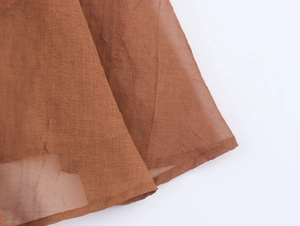 Detail shot of the lightweight brown fabric texture with pleated design and fine stitching