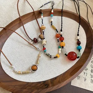 Ethnic beaded necklaces with resin stones and wood pendants in a rustic wooden tray