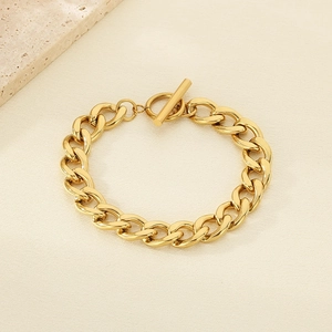 Close-up of 18K gold plated Cuban chain bracelet with OT toggle clasp on textured stone