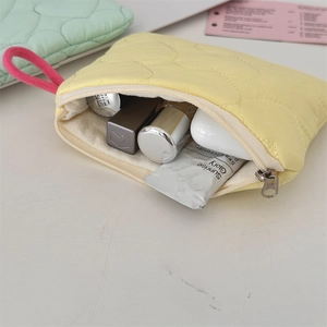 Quilted yellow sanitary pouch showing storage of cosmetics with a pink loop handle
