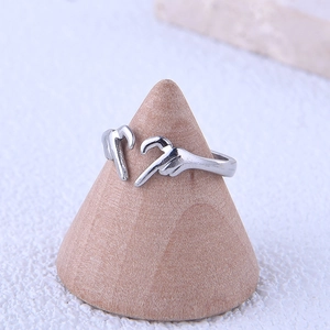 Detailed view of silver heart gesture ring on a wooden stand, open adjustable band style
