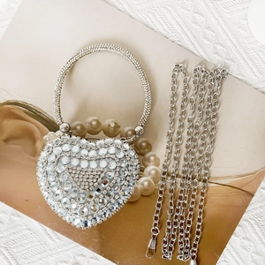 Macro shot of sparkling silver heart-shaped evening bag with crystal rhinestones and chain strap