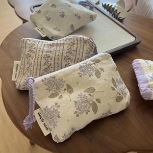Three-piece floral cotton mini pouch set with purple zip pulls on a wooden tray