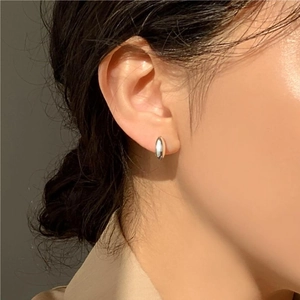 Close-up of polished silver hoop earring on ear showing sleek minimalist oval design