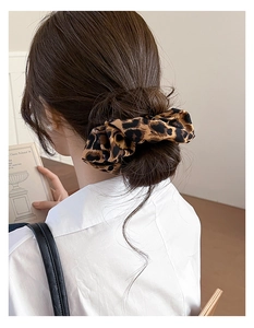 Detail of leopard print scrunchie used on a high bun hairstyle with soft fabric texture