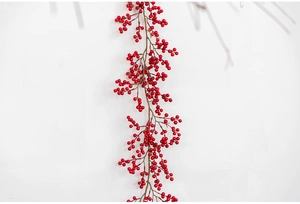 Close-up of vibrant red artificial Christmas berries against a clean white wall background