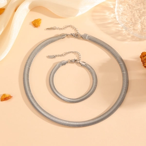 Silver flat snake chain necklace and bracelet set displayed on elegant silk fabric