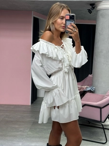 Detailed view of layered ruffles on the white off-shoulder dress with bell sleeves