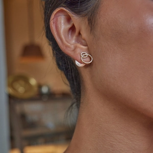 Close-up of elegant gold interlocking circle earrings with inlaid diamonds on ear