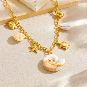 Gold stainless steel ocean necklace with seashell, sea turtle and starfish charms on sand