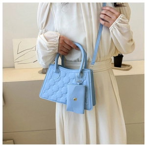 Close-up of light blue quilted handbag with M-embossed texture and matching card holder pouch