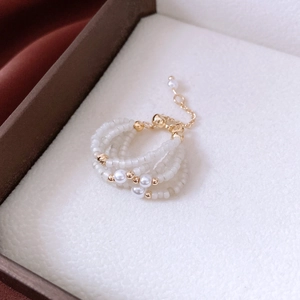 Detail of multi-layer glass bead ring with faux pearls and adjustable gold metal chain