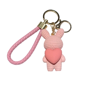 Pink knitted-style bunny keychain with heart charm and woven wrist strap for bags