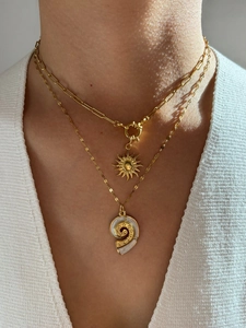 Close-up of layered gold sun and seashell pendant necklace on woman's neck