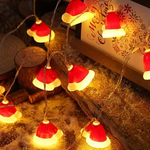 Detail of Santa hat shaped LED string lights with warm yellow glow on a snowy wood log