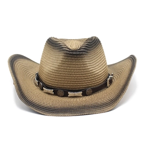 Detail of woven straw cowboy hat featuring vintage leather band with metal star ornaments