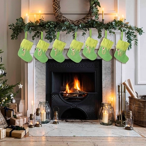 Green knitted Christmas stockings with gold JOY SNOW embroidery hanging on a festive mantel