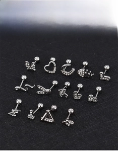 Detailed close-up of threaded silver ear studs with zircon heart, moon, and crown shapes