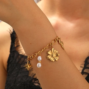 Élégant bracelet chaîne doré avec pendentifs marguerites et perles au poignet d'une femme