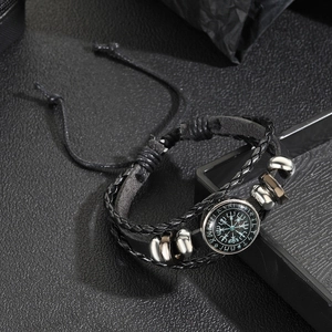 Close-up of a black leather braided bracelet with a glass Viking compass charm and metal beads
