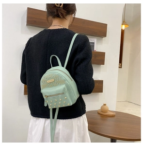 Detail of mint green PU leather backpack with gold studs and earphone hole design