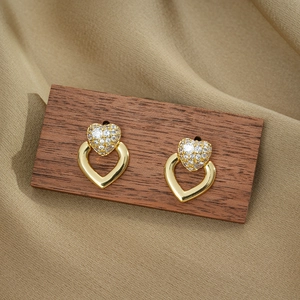 Elegant gold double heart stud earrings with sparkling cubic zirconia on textured background