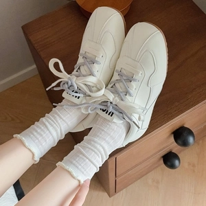 Beige vintage sneakers with ruffled white socks on a warm wooden background scene