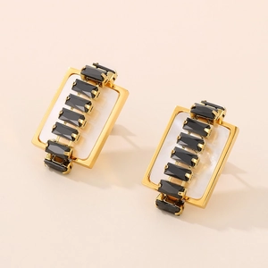 Macro view of gold rectangle stud earrings with black gemstone and pearly inlay