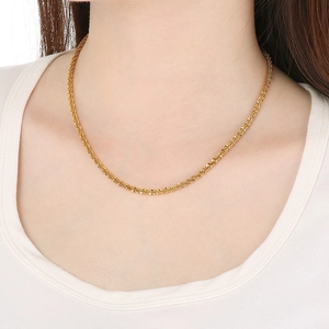 Detail view of a gold-toned stainless steel twist rope chain necklace worn on a model