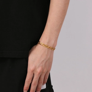 Close-up of a gold-toned Cuban link chain bracelet worn on a wrist for size reference