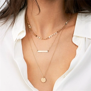 Close-up of triple-layered gold stainless steel necklace with geometric pendants on a model