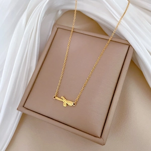Detail shot of a minimalist gold dragonfly pendant on a fine titanium steel chain necklace