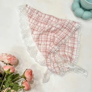 Detailed flat lay of pink checkered headscarf with white lace edges and pom-pom trim