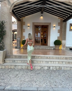 Back view of mint green sequin evening gown featuring an open back and high slit
