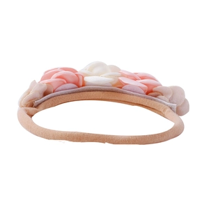 Detail of baby elastic headband featuring soft pink and cream fabric flowers on white base