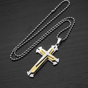 Detail of layered gold and silver cross pendant with metallic beaded necklace chain