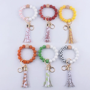 Dettaglio di vari portachiavi a bracciale in silicone a tema sportivo con nappe in pelle